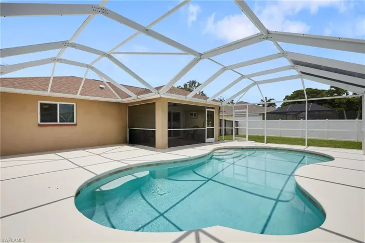 View of pool featuring a patio area, a ceiling fan, a sunroom, and glass enclosure