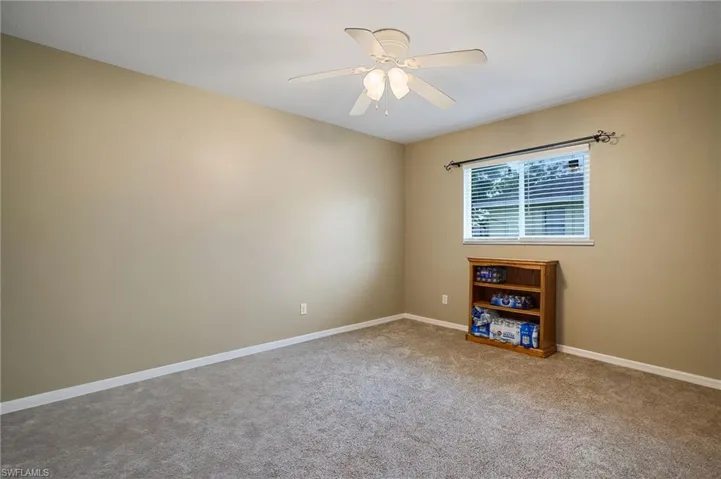 Carpeted spare room with a ceiling fan and baseboards