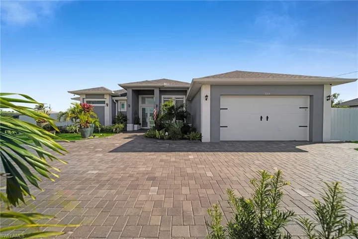 Prairie-style home featuring stucco siding, decorative driveway, and an attached garage