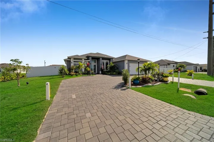 View of front of house with a front lawn, decorative driveway, and a garage