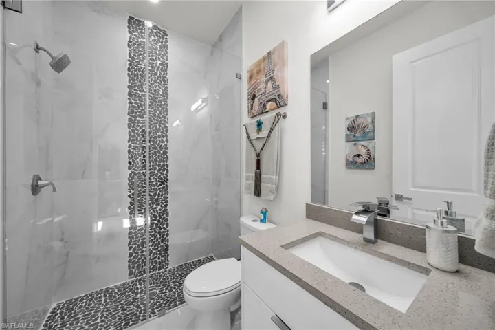 Full bath featuring vanity and a marble finish shower
