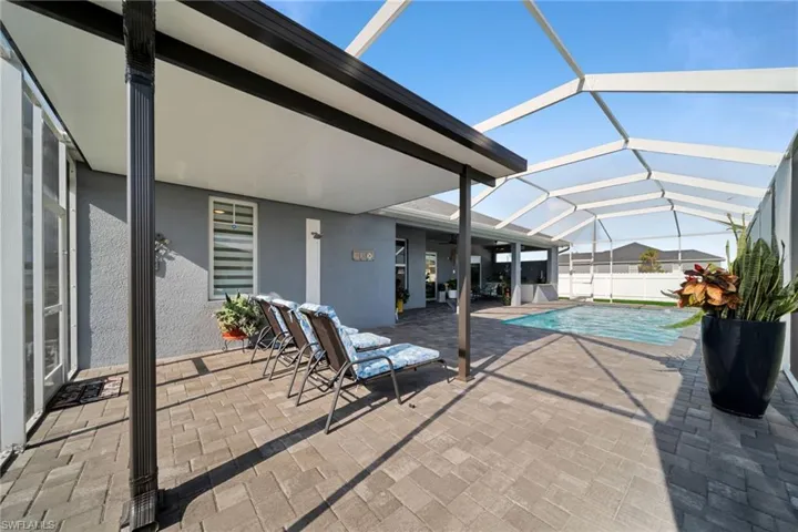 View of swimming pool with a sunroom, a patio area, and glass enclosure