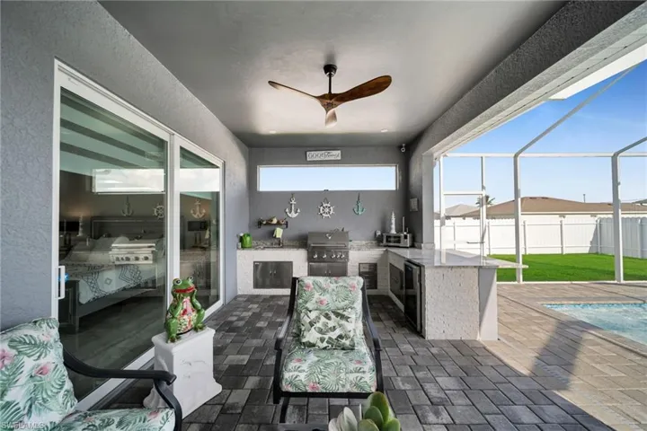 View of patio / terrace with exterior kitchen, ceiling fan, a sunroom, glass enclosure, and an outdoor pool