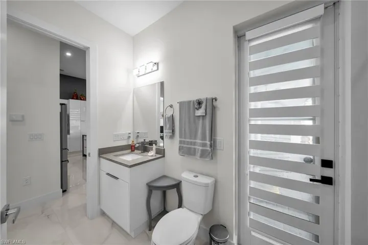 Half bath with vanity and light marble finish floors
