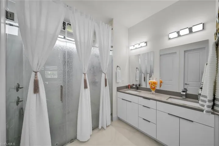 Full bathroom with double vanity and a stall shower