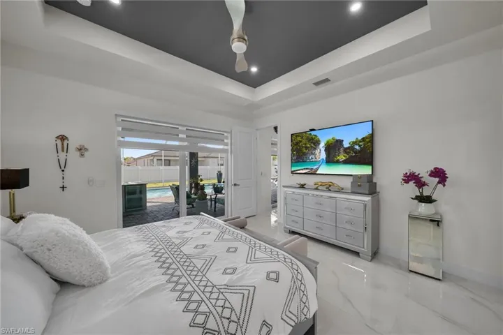 Bedroom with a tray ceiling, access to outside, a ceiling fan, recessed lighting, and light marble finish flooring