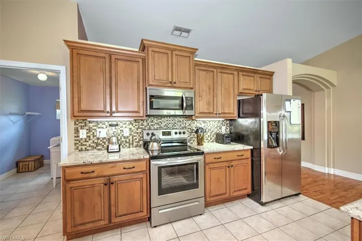 Kitchen view of SS appliances, oversized cabinets, granite counter tops and back splash. Under cabinet lighting as well.