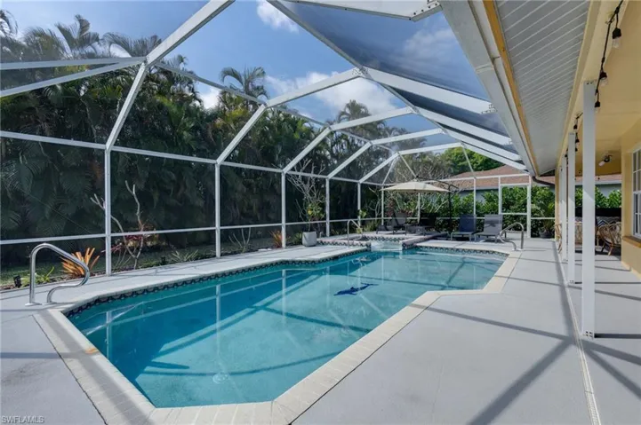Outdoor pool with a patio area, glass enclosure, and a sunroom