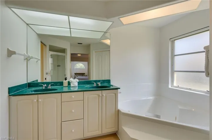 Bathroom with double vanity, a stall shower, and a jetted tub