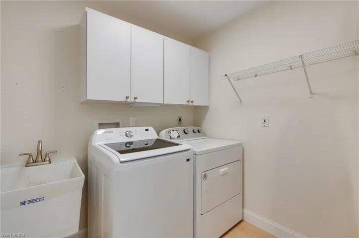 Laundry area with washing machine and dryer, cabinet space, and light wood finished floors