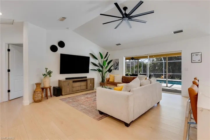 Living area featuring a sunroom, a ceiling fan, lofted ceiling, and light wood-style flooring