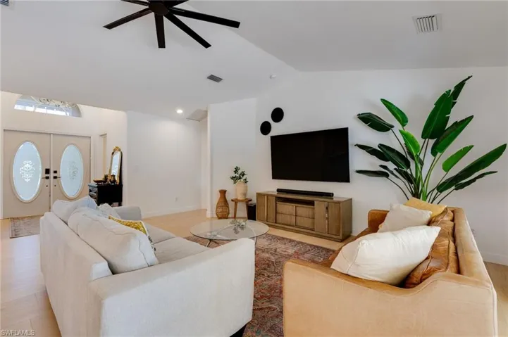Living room featuring ceiling fan, light wood-style floors, and lofted ceiling