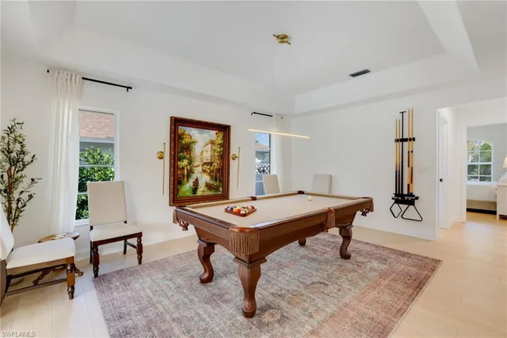 Game room featuring a raised ceiling, pool table, and light wood-style flooring