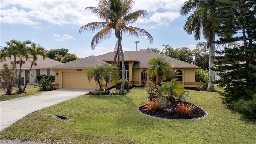 Ranch-style house with a garage, driveway, stucco siding, and a front lawn