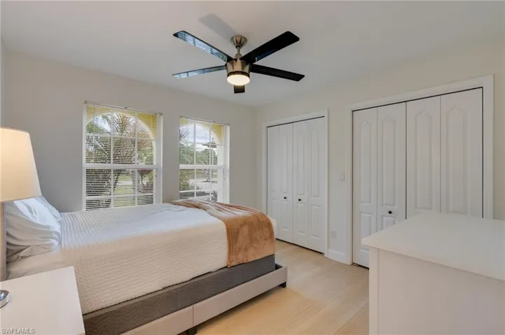 Bedroom featuring two closets, light wood finished floors, and a ceiling fan