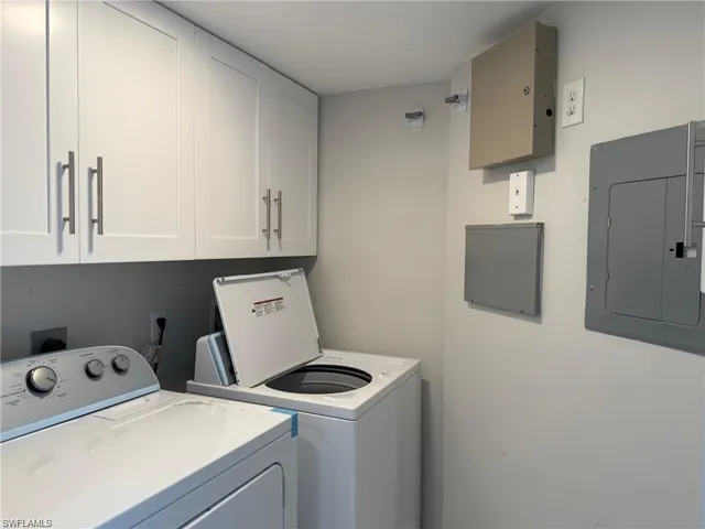 Laundry room with electric panel, independent washer and dryer, and cabinet space