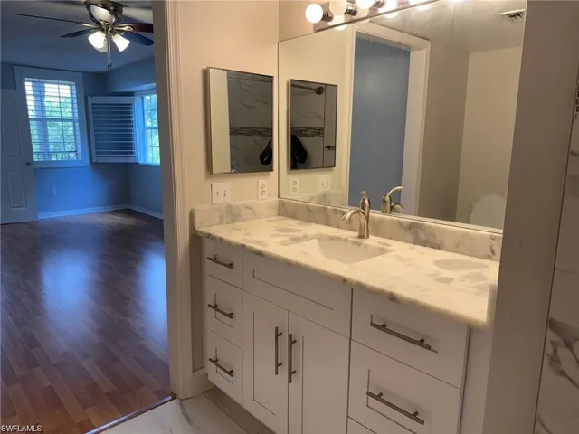 Primary Bathroom featuring vanity, a ceiling fan, and light wood-style flooring