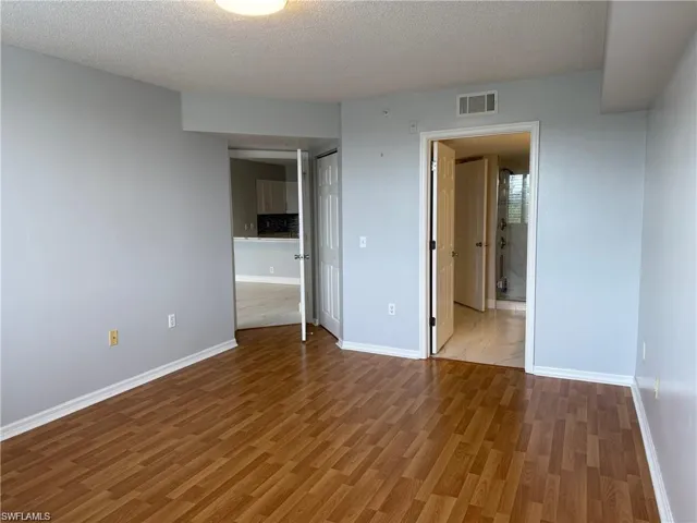 Guest bedroom featuring a textured ceiling, wood finished floors, and a closet