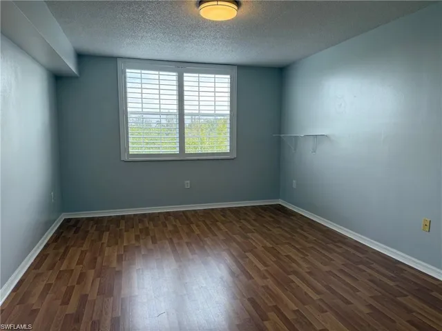 Guest room with dark wood-style flooring and a textured ceiling