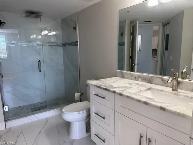 Guest Bathroom with a marble finish shower, vanity, and marble look tile flooring