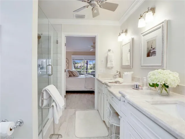 Bathroom with wood-type flooring, dual vanity, ceiling fan, and crown molding