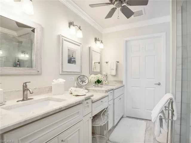 Bathroom featuring crown molding, tile floors, ceiling fan, oversized vanity, and dual sinks