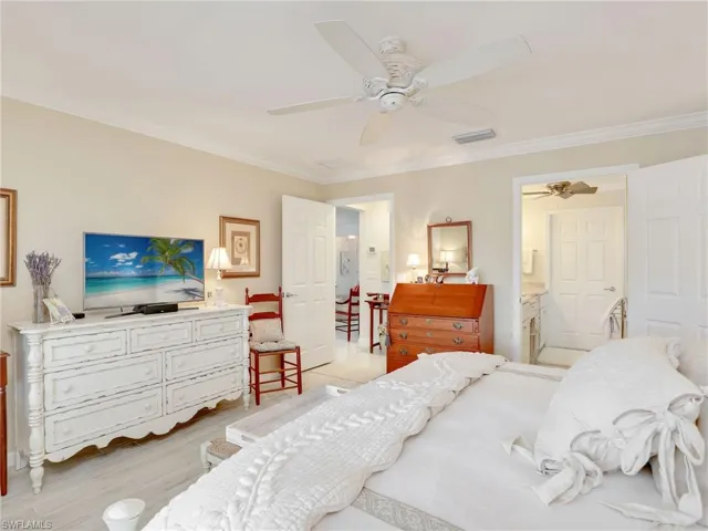 Bedroom with ceiling fan, connected bathroom, light wood-type flooring, and ornamental molding