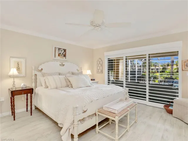 Bedroom with ceiling fan, light wood-type flooring, and ornamental molding
