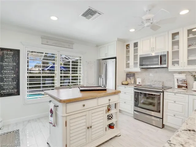 Kitchen with ceiling fan, light hardwood / wood-style flooring, tasteful backsplash, stainless steel appliances, and white cabinets