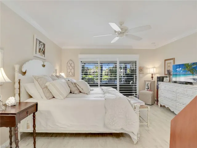 Bedroom featuring light wood-type flooring, ornamental molding, and ceiling fan