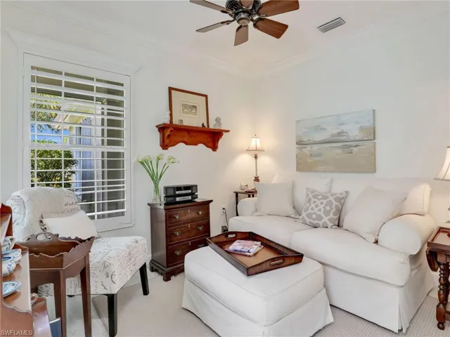 Living room with light carpet, ornamental molding, and ceiling fan