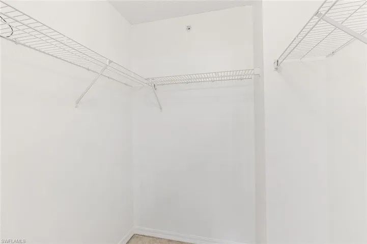 Large walk-in closet featuring white wire shelving and hanging rods