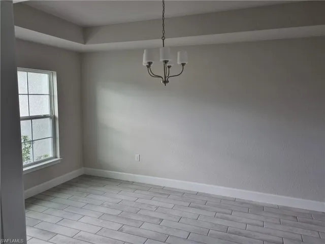 Unfurnished room with a notable chandelier