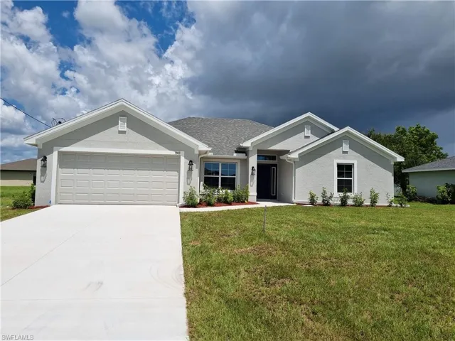 View of front of property with a garage and a front lawn