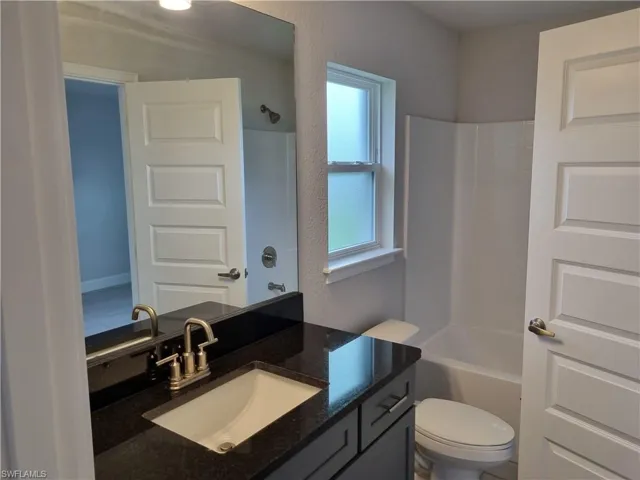 Full bathroom featuring vanity, washtub / shower combination, and toilet