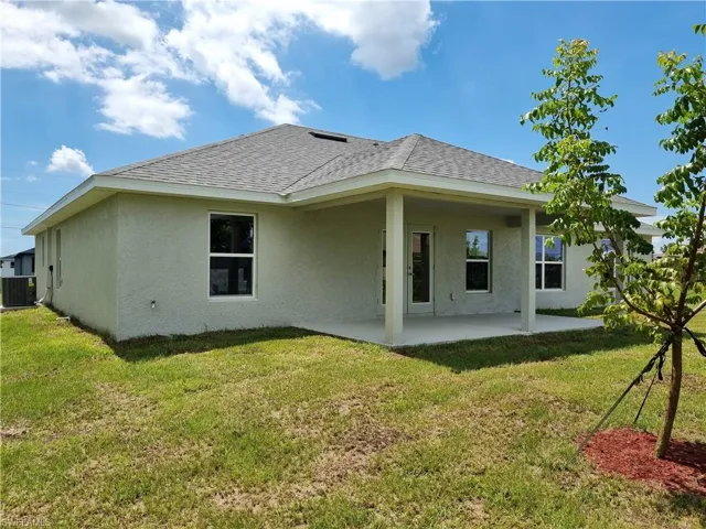 Back of house with cooling unit, a yard, and a patio area