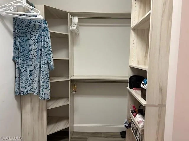 Walk in closet with dark hardwood / wood-style floors