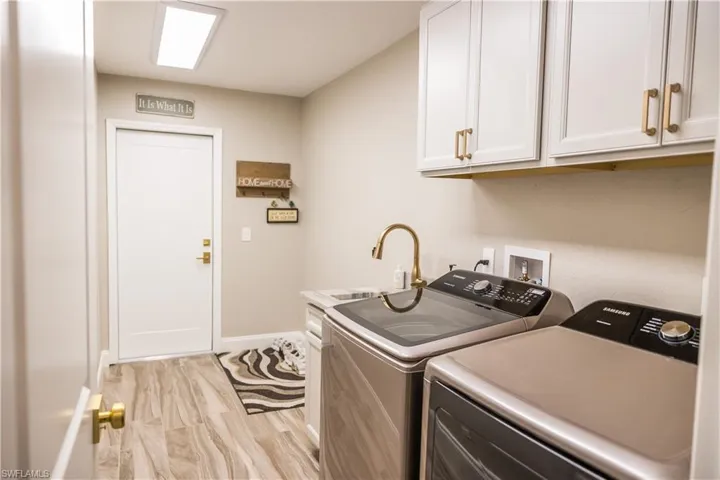 Laundry area featuring cabinets, washing machine and dryer, sink, and light hardwood / wood-style flooring