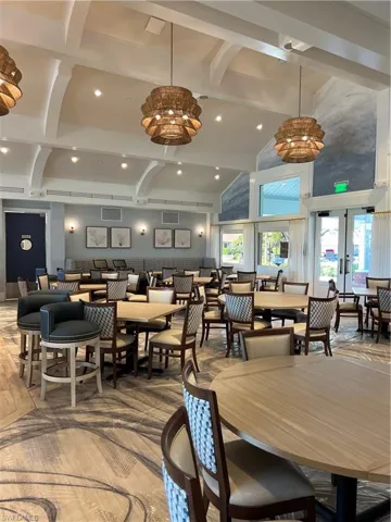 Dining space with beamed ceiling, a towering ceiling, wood-type flooring, and french doors