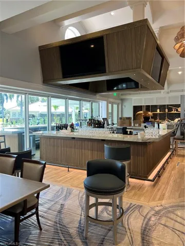 Bar with high vaulted ceiling and light hardwood / wood-style flooring