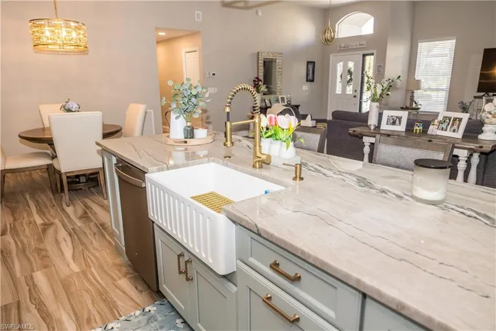 Kitchen with light stone counters, decorative light fixtures, sink, and a notable chandelier