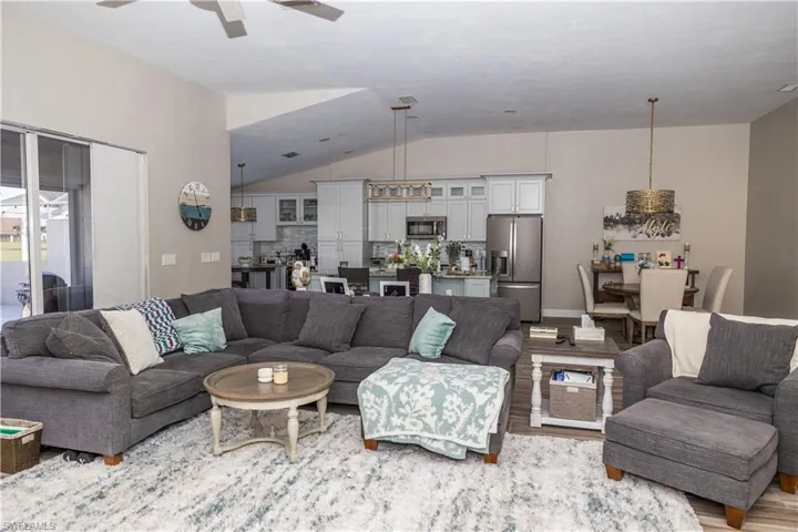 Living room with vaulted ceiling, ceiling fan, and light hardwood / wood-style floors