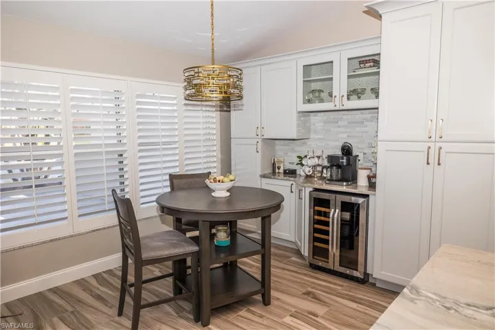 Dining space with bar, wine cooler, and light wood-type flooring