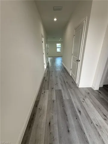 Recessed ceiling lighting, wood-finish flooring, white paneled doors, and natural light from a window