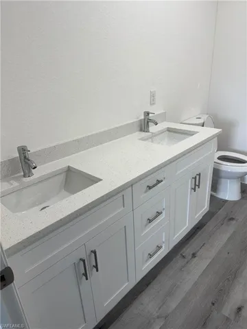Dual vanity with white shaker-style cabinetry, chrome hardware, integrated rectangular sinks, and a light-colored countertop