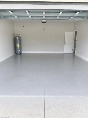 Expansive garage with a light gray epoxy floor coating, finished white walls, and a visible water heater