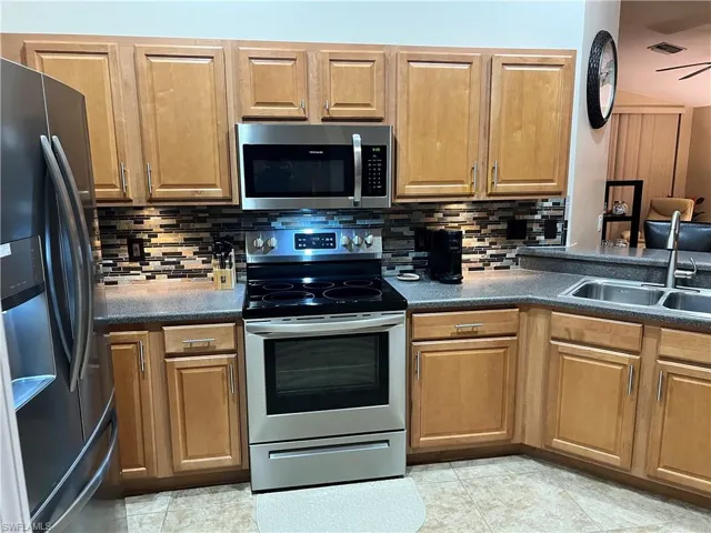 Kitchen with wood cabinets, decorative tile backsplash, under cabinet lighting, solid surface counter tops and stainless appliances.