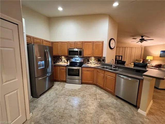Kitchen with peninsula open to the great room with volume ceiling and large upgraded tile flooring.