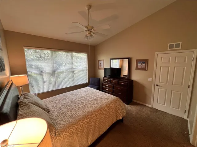 Spacious Primary Bedroom with carpet flooring and vaulted ceiling.