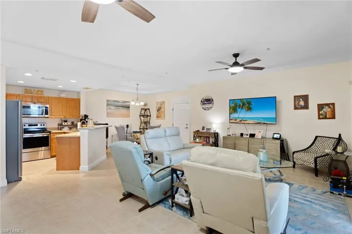 Living area featuring a ceiling fan, light tile patterned floors, recessed lighting, and a chandelier